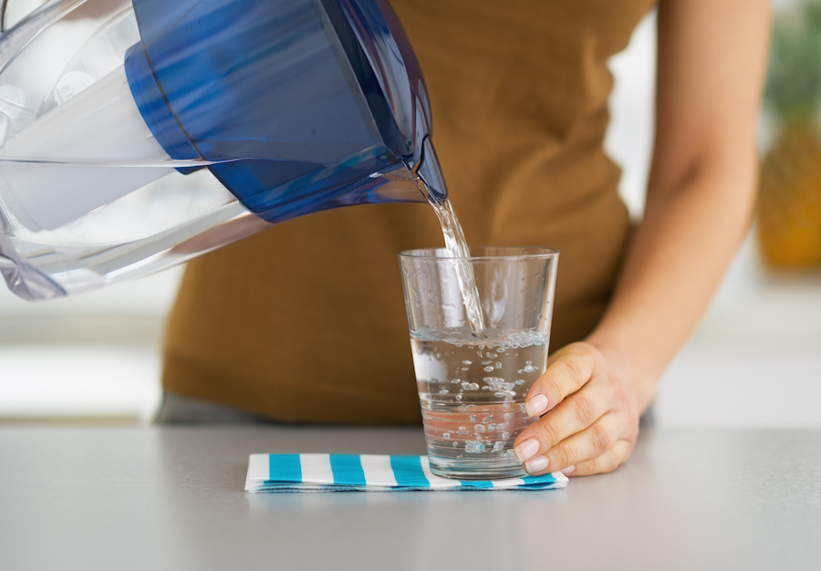 woman pouring water from water filter pitcher