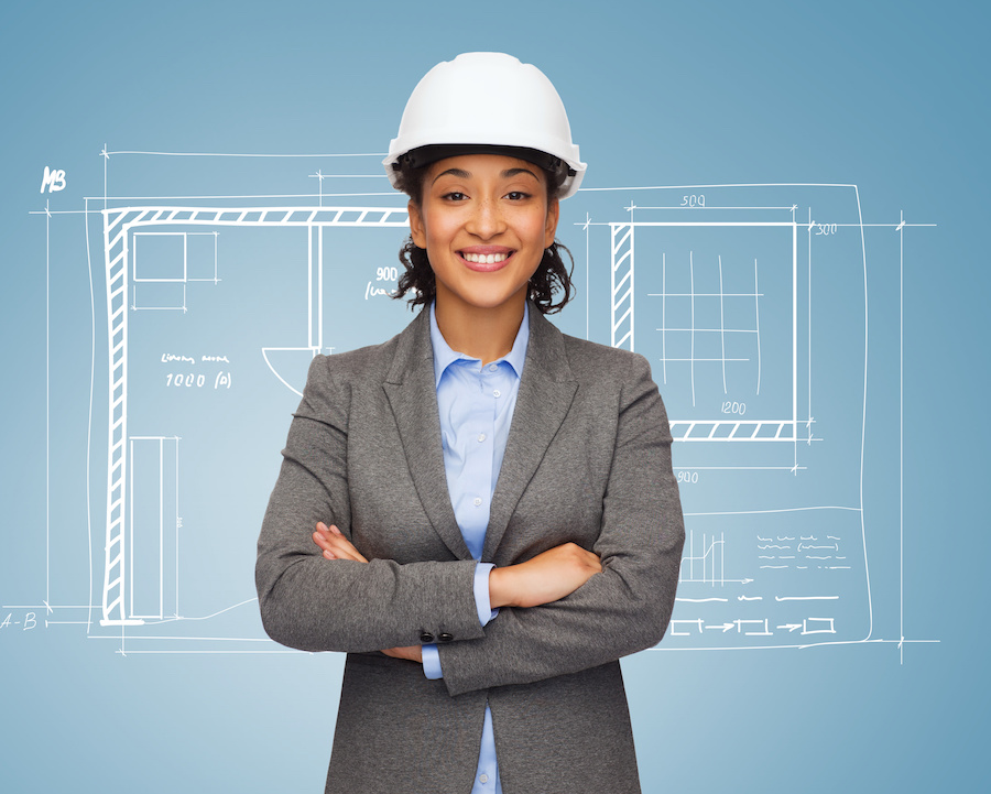 Woman in hard hat standing in front of blueprint