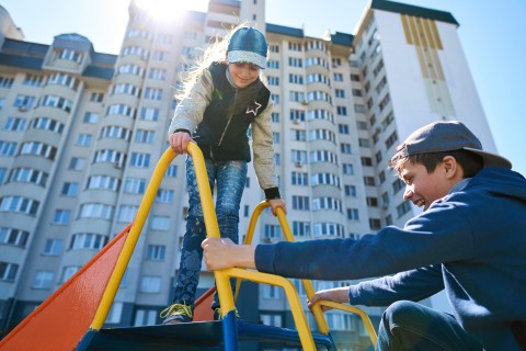 two kids playing on a playground in front of a building